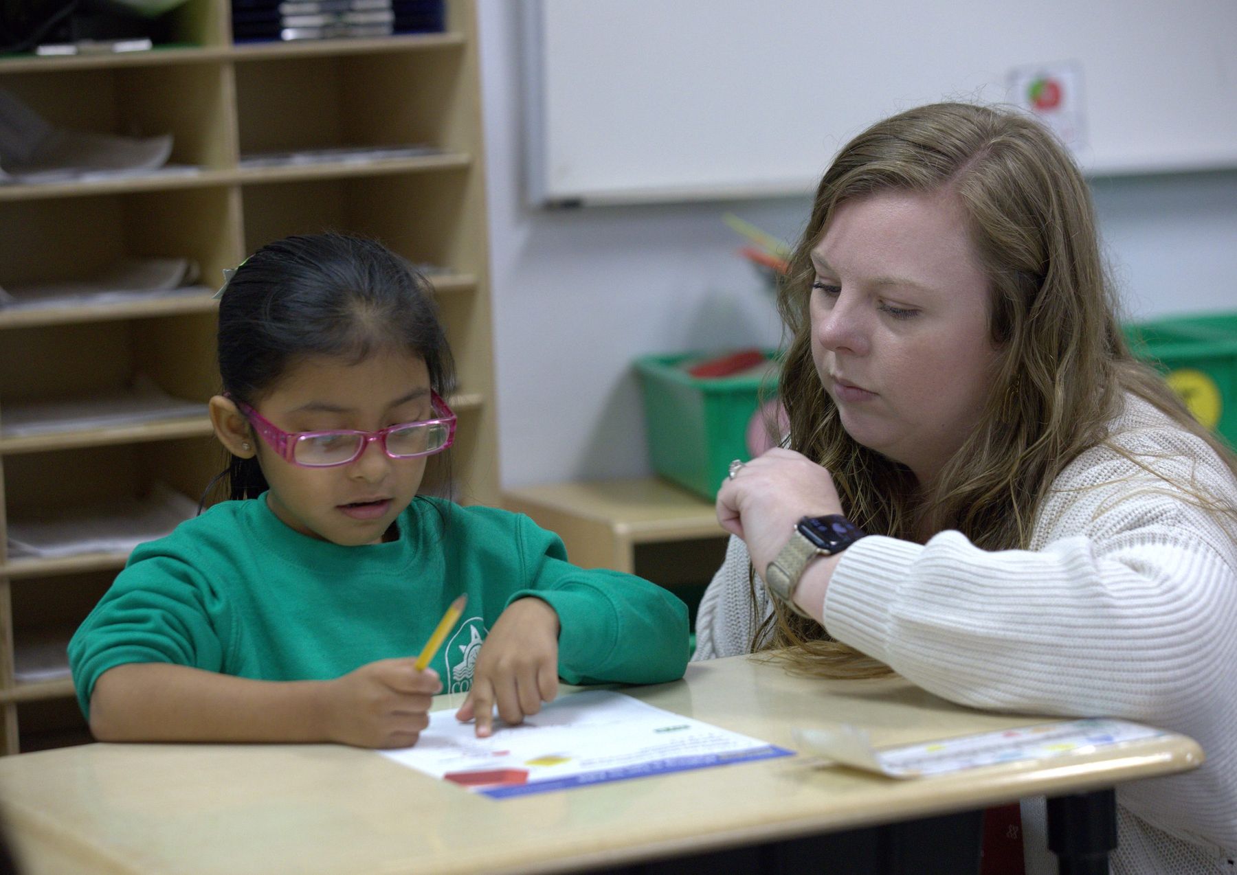 Compass teacher helping a young student with her work