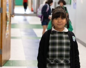 Compass Berclair student in uniform smiling in the school hallway