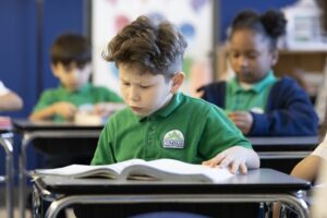 Compass Berclair student reading a book at his desk