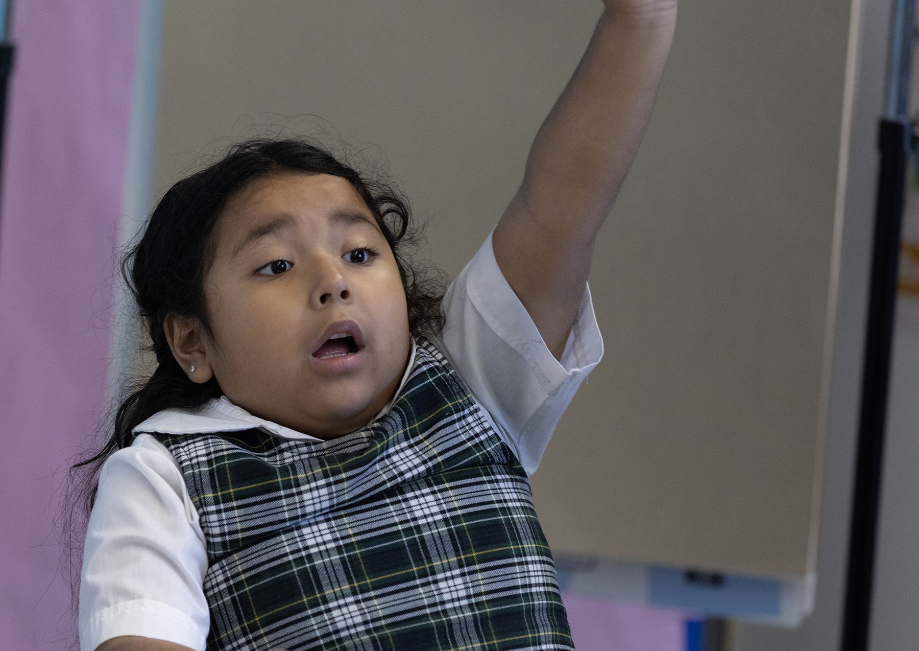 Young Compass student raising her hand in class